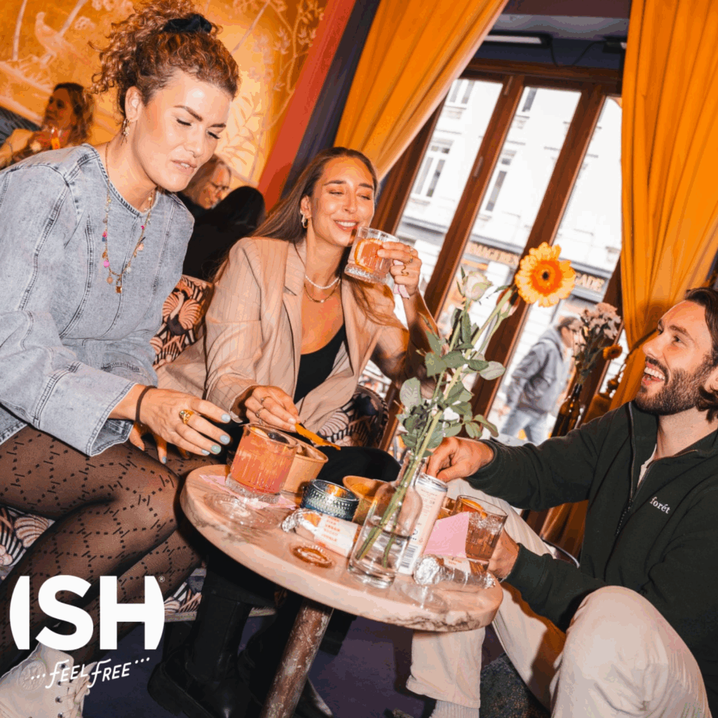 Ish Spirits przedstawiających ludzi siedzących w restauracji i pijących wino i prosecco bezalkoholowe oraz koktajle premium bez zawartości alkoholu.